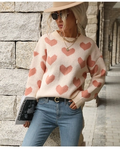Detail of soft knit pink heart jacquard pattern on a white sweater in outdoor light