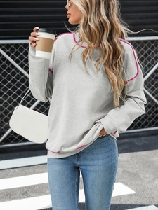 Detail of light grey sweatshirt with vibrant pink piping trim on neckline and shoulder