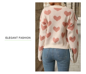 Close-up of beige knit sweater with pink heart patterns and elegant ribbed round neck
