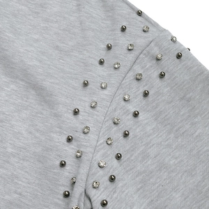 Macro view of light grey hoodie fabric with studded beads and sparkling rhinestone detail