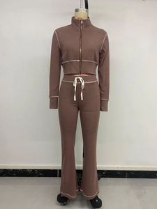 Detail eines schokoladenbraunen Trainingsanzugs mit weißen Kontrastnähten und Zip-Jacke