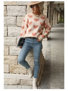 Detail shot of crew neck sweater featuring pink heart jacquard patterns on beige knitwear