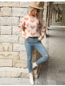 Detailed close-up of pink heart patterns on the white knit sweater for women