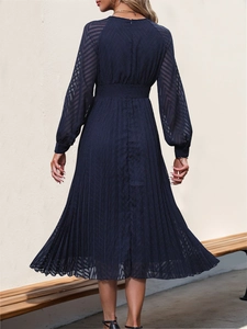 Detail of dark blue pleated dress featuring long sheer sleeves with geometric patterns