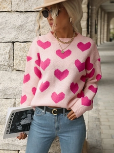 Detail of pink knitted sweater showing red heart patterns and soft textured fabric