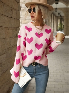 Detail of pink knitted sweater with red heart patterns and soft ribbed crew neck finish