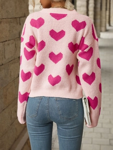 Detail view of the pink knitted sweater back showing heart patterns and ribbed hem textures