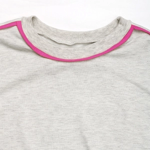 Detail of grey marl sweater showing ribbed crew neck with pink contrast piping edge