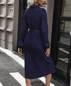 Back view of a long-sleeved navy blue shirt dress with a waist belt and elegant drape