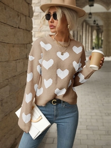 Detail shot of khaki knit sweater featuring white heart patterns and ribbed cuffs