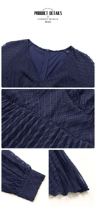 Detail of navy blue V-neck dress featuring jacquard texture and elegant pleated hem