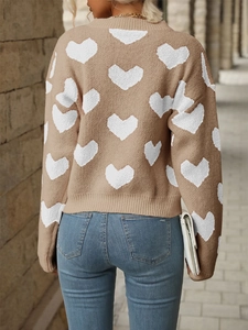 Detail of light brown knit sweater with white heart patterns and ribbed hem detail
