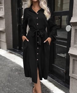 Detail of a black long-sleeve shirt dress with pink buttons and a waist tie belt