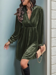 Dettaglio elegante abito in velluto verde scuro con scollo a V e polsini a volant