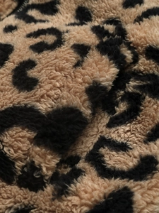Gros plan sur le tissu en fausse fourrure léopard et les détails zippés d'une veste d'hiver