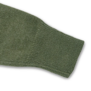 Gros plan d'un pull en maille vert herbe montrant les poignets côtelés et la texture