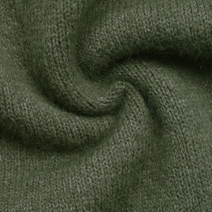 Gros plan d'un tricot vert foncé montrant une texture pelucheuse et des fibres de mohair