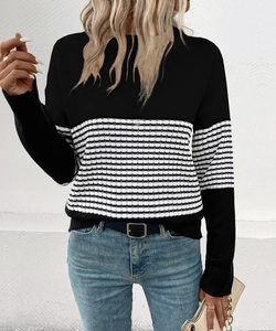 Detail of a women's black and white striped long-sleeve knit sweater with ribbed texture