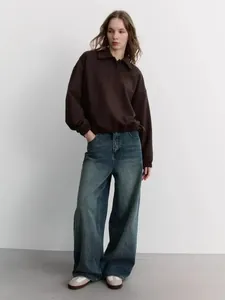 Close-up of the dark brown polo collar sweatshirt with elastic cuffs and retro jeans