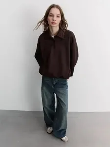Full view of women's dark brown long-sleeved polo sweatshirt and blue-grey wide-leg jeans