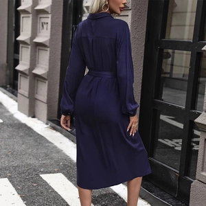 Navy blue long sleeve shirt dress with waist tie and pleated back in a city street setting