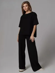 Close-up of black casual two-piece set featuring round neck top and wide-leg pleated trousers
