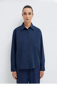 Detail of navy blue button-down shirt with chest pocket and curved hem for women
