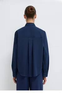 Detail of navy long sleeve shirt back with pleated yoke and curved hemline