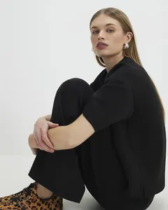 Detailed view of black two-piece set styled with leopard sneakers and silver jewelry