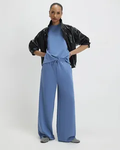 Women's blue cotton tracksuit paired with a glossy black leather jacket and checkered flats