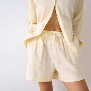 Women's summer two-piece lounge set with button-down shirt and drawstring shorts in pale yellow