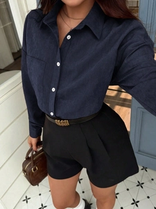 Dunkelblaue Damenbluse mit langen Ärmeln, weißen Knöpfen und schwarzen Shorts