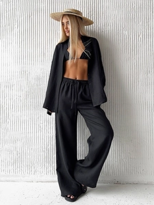 Detail of a black three-piece cotton set with relaxed shirt, bikini top, and wide-leg trousers