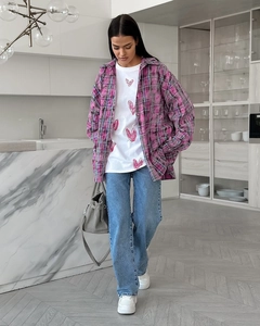 Détail d'une chemise à carreaux femme avec t-shirt imprimé cœur et jean bleu classique