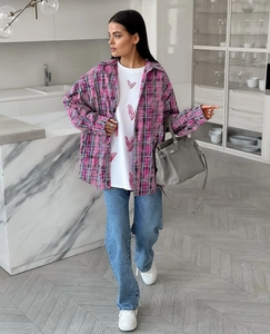 Gros plan sur une chemise à carreaux rose oversize portée avec un t-shirt blanc à motif