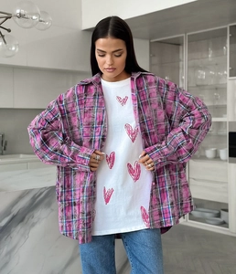 Détail d'une chemise en flanelle à carreaux rose sur un t-shirt blanc avec cœurs