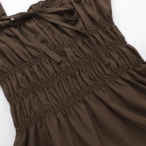 Detail of dark brown mini dress featuring elastic smocked fabric and small bow detail