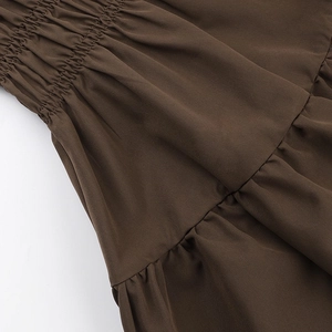 Macro detail of brown smocked waist fabric and ruffled hem on a mini dress