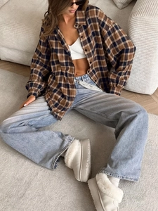 Close-up of a women's plaid shirt paired with a white ribbed tank top and blue wide-leg jeans