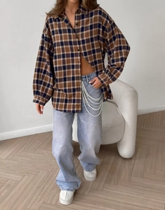 Detail view of plaid shirt styled with light blue wide-leg jeans and pearl waist chains