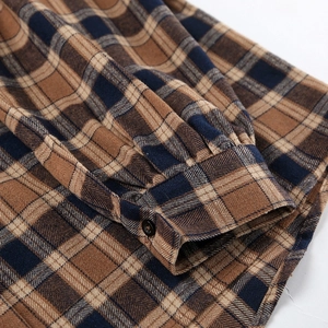 Detail view of a plaid shirt cuff with a black button and fine stitching details