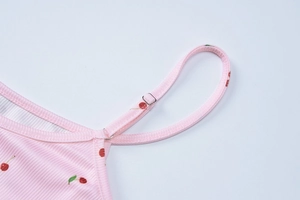 Detail of floral pink camisole dress featuring cherry print and adjustable straps