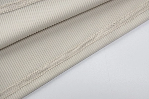 Dettaglio del tessuto a maglia a coste e della cucitura piatta a doppio ago sull'abito beige