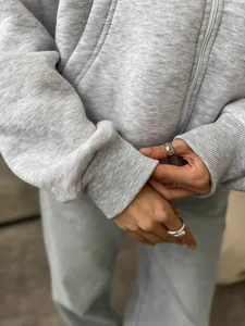 Close-up of ribbed cuffs and thick cotton fabric texture on a grey zip-up hoodie