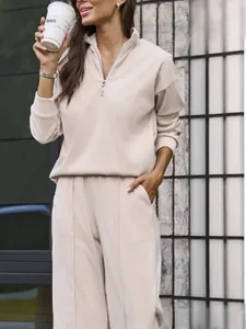 Detail of beige half-zip sweatshirt and straight-leg trousers with vertical seams