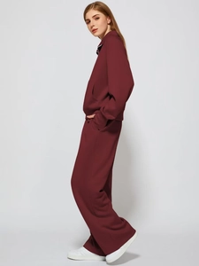 Detail of burgundy two-piece tracksuit featuring a high collar zipper and wide-leg pants