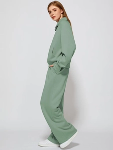 Detailed side view of women's two-piece sage green tracksuit with zipper and wide-leg pants