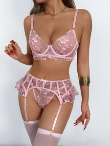 Dettaglio del ricamo floreale rosa e fiocchi di raso sul set di lingerie