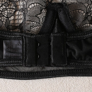 Detail of double hook-and-eye closure on a black lace bra with fine mesh texture