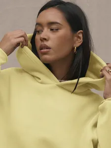 Close-up of light yellow hoodie featuring premium knit texture and relaxed hood design